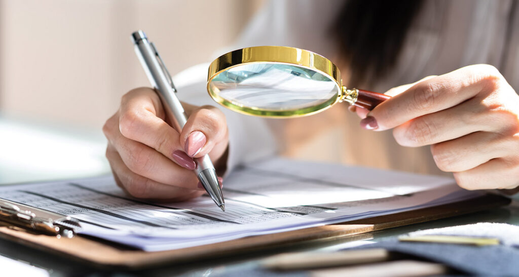 Corporate Auditor Using Magnifying Glass For Tax Fraud Audit