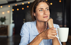 Thoughtful,Mature,Woman,Sitting,In,Cafeteria,Holding,Coffee,Mug,While